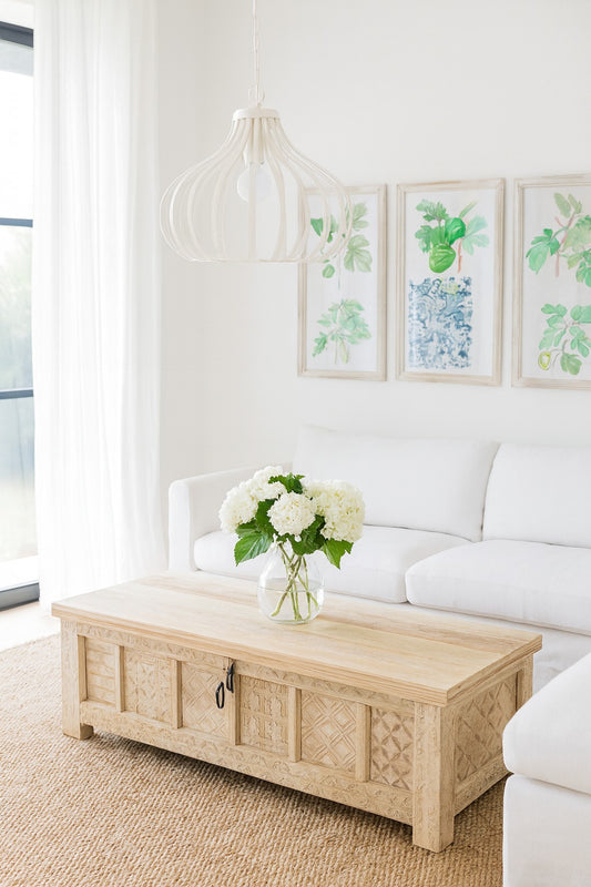 Living room with a white sofa, wooden coffee table, and framed artwork on the wall.
