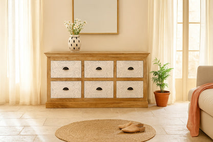 Wooden dresser with six drawers in a room with a plant and rug.
