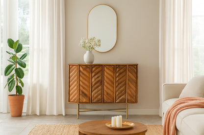 Wooden sideboard in a living room with a mirror, plant, and candles.