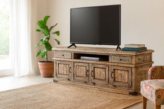 Wooden TV stand with a television and decor items in a room with a plant and chair.