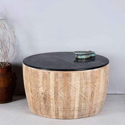 Round wooden table with black marble top on a light gray background