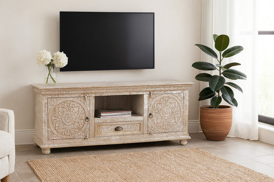 TV on a decorative wooden stand in a living room with a plant and rug.