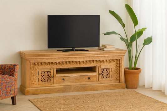 Wooden TV stand with decorative carvings, black TV, and plant in a living room setting.